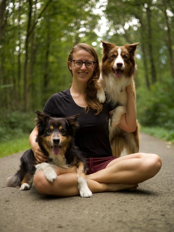 Bianca Glatz von der Hundeschule Smartdogs Hundetraining in Reutlingen, sitzt im Schneidersitz. Auf ihrem Schoß und auf der Schulter ihre Border Collies Maddox und Ayx