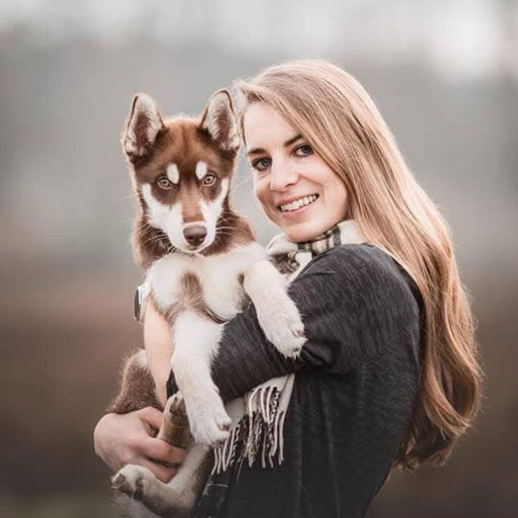 Nina Cappello hält Huskywelpe Dreki auf dem Arm und lächelt in die Kamera